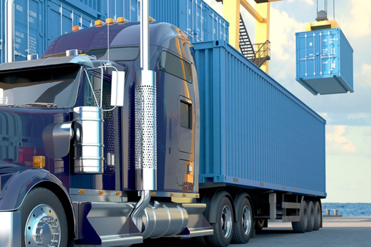 Container truck at a quayside yard while a crane lifts a container overhead